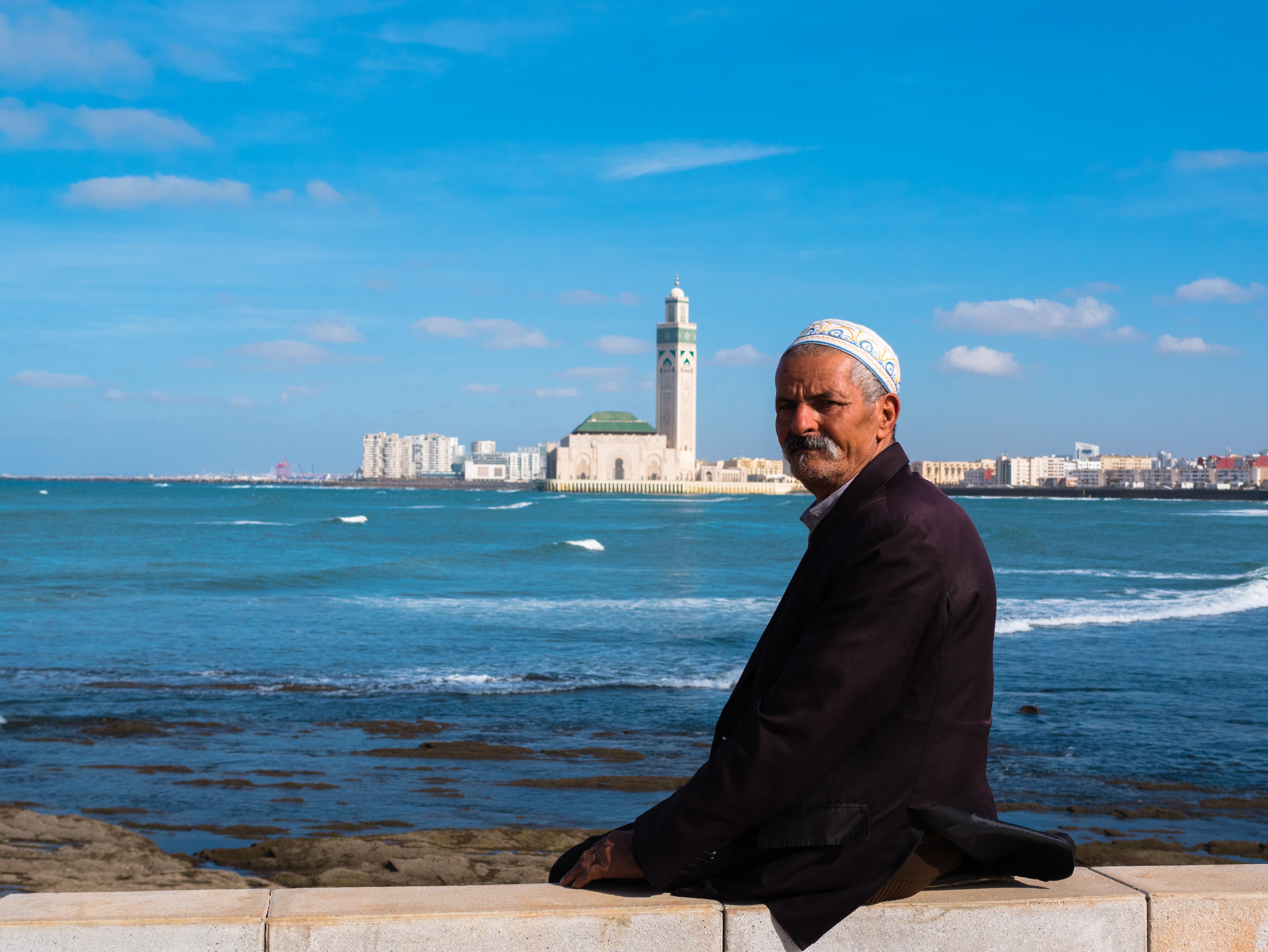 Man sitting across bay from Hing Hussein II mosque, Casablanca